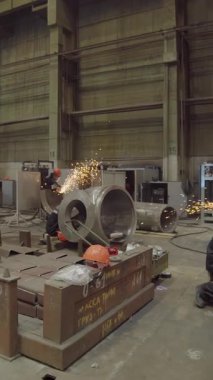 Metal bileşenleri öğüten, endüstriyel üretim süreçlerini sergileyen fabrika işçileri.