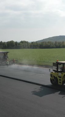 Yol silindirleri ve kaldırımlar yeni bir asfalt yolda çalışıyor