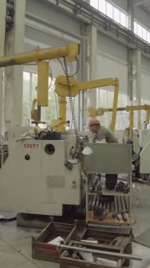 Torna makinesi çalıştıran fabrika işçisi yoğun bir endüstriyel ortamda metal parçaları üretiyor.