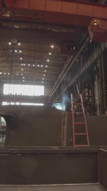 Endüstriyel işçiler büyük bir fabrikada metal parçaları üretiyorlar.