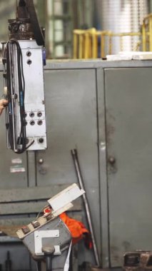 Büyük bir metal torna işleten sanayi işçisi fabrika ortamında metal bir detay üretiyor.