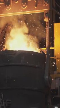 Turuncu erimiş metal, çelik fabrikasında dev bir kepçeye dökülüyor.