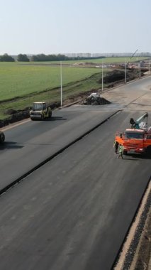 İşçiler ve makineler kırsal alanda yeni bir asfalt otoyol inşa ediyorlar.