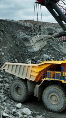 Büyük kazıcı sarı maden kamyonuna cevher yüklüyor.