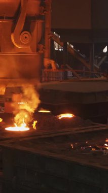 Dökümhane işçileri yoğun endüstriyel ortamda erimiş metali kalıplara dikkatlice döküyorlar.