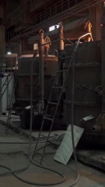 Endüstriyel işçiler bir metal dökümhanesinde, erimiş metal dökme ve dökme sürecini gösteren bir fırın işletiyorlar.