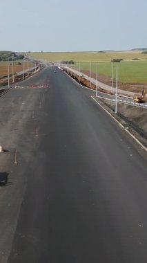 Yeni bir otoyola asfalt döşeyen ve sokak lambaları takan yol işçileri