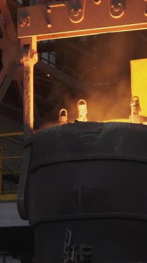 Endüstriyel vinç çelik fabrikasındaki konteynıra erimiş metal döküyor.