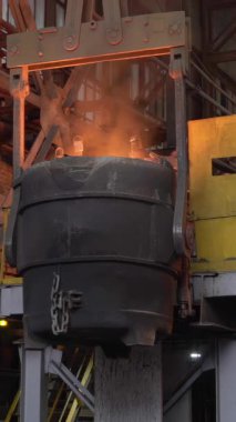 Erimiş metal, çelik fabrikasındaki büyük bir konteynırdan başka bir konteynere dökülüyor.