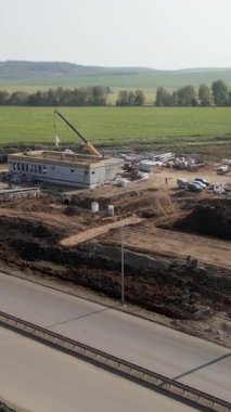 İnşaat işçileri otoyolun yakınına vinç kaldırma malzemeleri ile yeni bir yapı inşa ediyorlar.