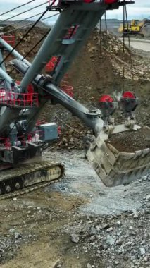 Büyük kazıcı madencilik alanında taşları çöp kamyonuna yüklüyor.