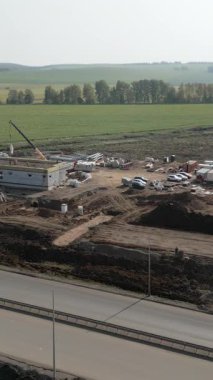 İnşaat işçileri kırsal bir alanda otoyolun yakınında bir yapı inşa ediyorlar.