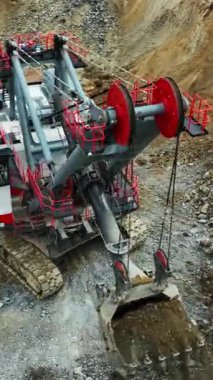 Büyük kazıcı açık maden ocağındaki çöp kamyonuna taş yüklüyor.