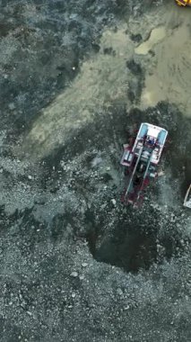 Eklemli nakliye kamyonu taş ocağındaki çukura çakıl boşaltıyor.