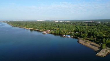 Sakin nehir, gün doğumunda berrak mavi gökyüzünün altındaki şehir manzarasını yansıtıyor. Kırp