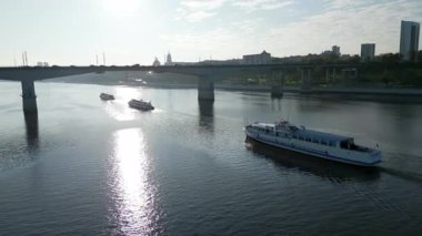 Moskova, Rusya 'da gün doğumunda Moskva nehrinde köprüden geçen beyaz yolcu feribotu. Kırp