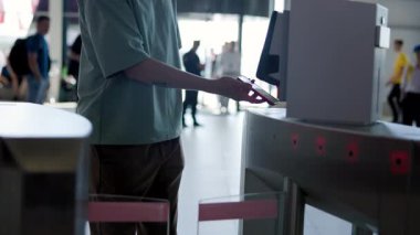 Yoğun bir ulaşım merkezindeki turnikelerden geçmek için akıllı telefon teknolojisini kullanan yolcular. Medya