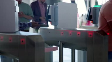 Havaalanı terminalindeki otomatik kapılardan geçmek için akıllı telefon ve bilet kullanan yolcular. Medya