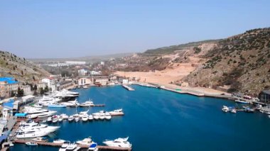 Balaklava körfezinin güzel mavi sularına demirlenmiş lüks yat ve tekneleri gösteren hava manzarası. Medya