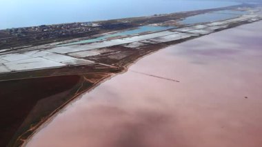 Pembe göl kıyısının havadan görünüşü ve açık mavi gökyüzünün altında tuz buharlaşması göletleri. Medya