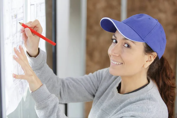 快乐的女建筑工人拿着铅笔和房子的平面图 — 图库照片