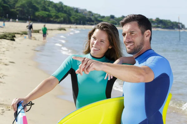 Succesvolle Paar Surfers Wijzend Naar Iets — Stockfoto