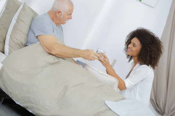 Vrouw Serveert Een Glas Water Aan Senior Man Bed — Stockfoto