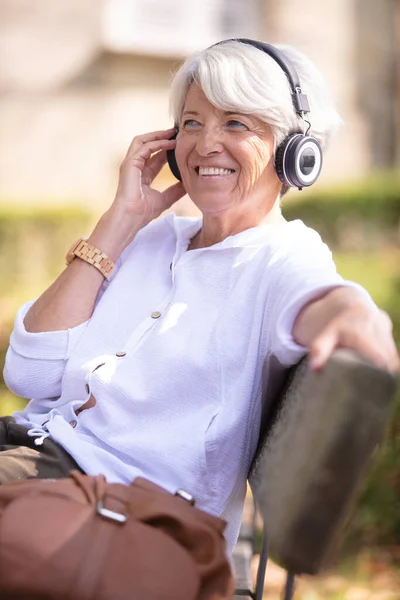 Χαμογελαστή Ηλικιωμένη Κυρία Που Κάθεται Ένα Παγκάκι Ακούγοντας Μουσική — Φωτογραφία Αρχείου