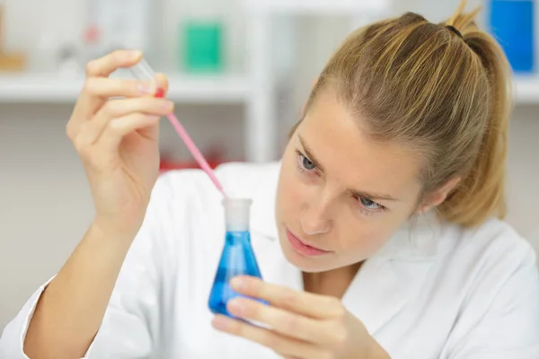 年轻的女技师在化学实验室里用长笛 — 图库照片