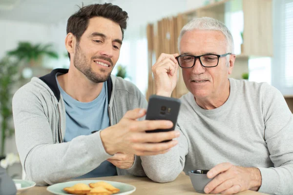 Syn Ukáže Svůj Telefon Svému Zralému Otci — Stock fotografie