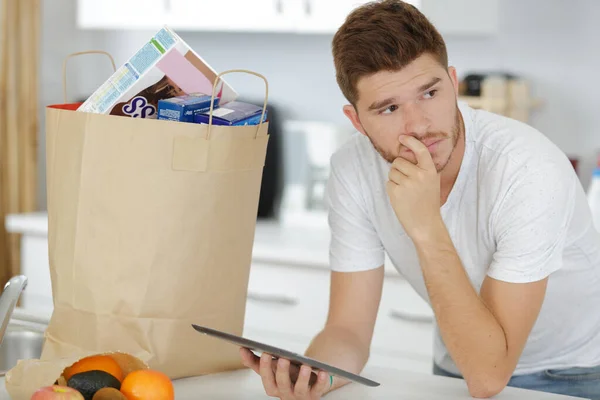 男人在纸袋旁边用平板电脑上网购物 — 图库照片