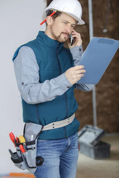 Construtor Masculino Está Olhando Para Prancheta Falando Por Telefone — Fotografia de Stock