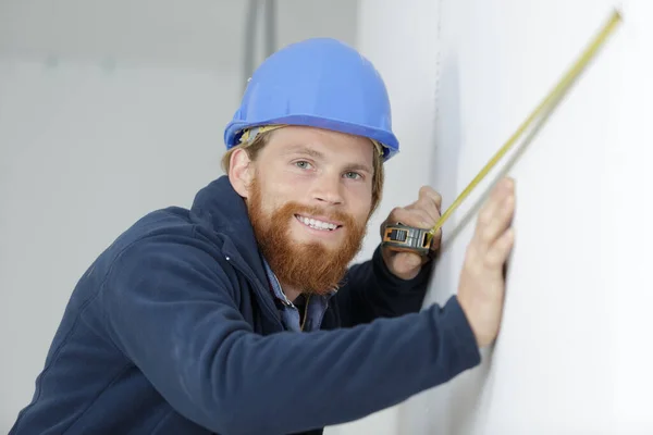 Happy Young Builder Measuring Wall — Stock Photo, Image