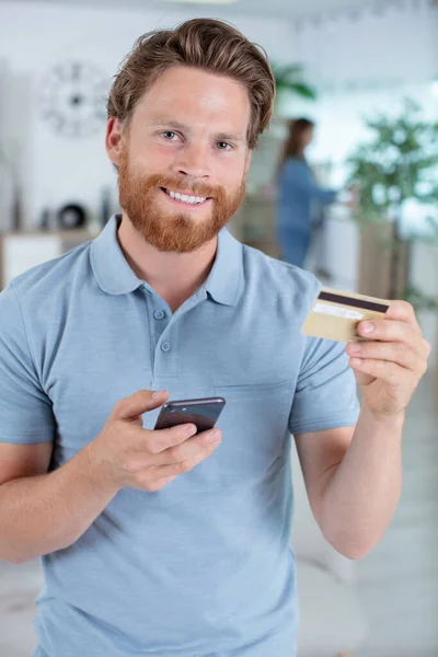 Szczęśliwy Młody Człowiek Trzyma Telefon Komórkowy Kartę Kredytową — Zdjęcie stockowe