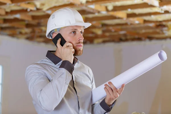 architect in development property holding plans and talking on telephone