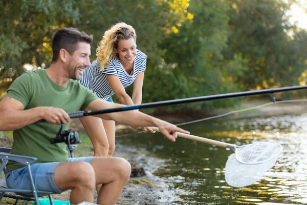 川のそばの若いカップル釣り — ストック写真