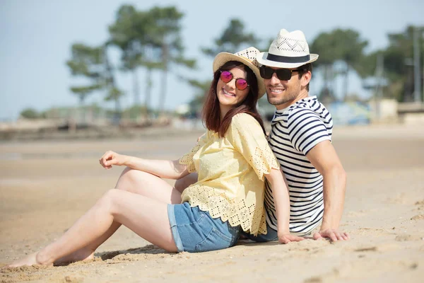 一对夫妇坐在沙滩上观看日落 — 图库照片