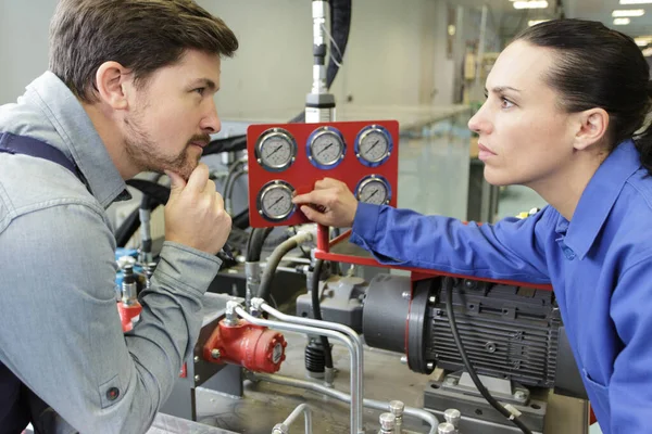 Vrouwelijke Werknemer Het Controleren Van Machine Meter Met Supervisor — Stockfoto