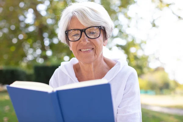 Senior Vrouw Lezen Boek Gelegd Het Gras — Stockfoto