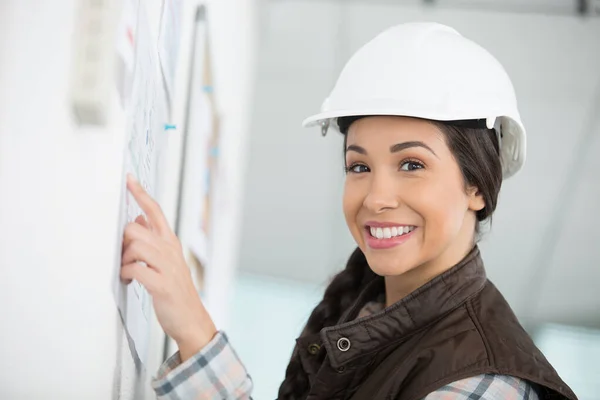 Female Worker Wearing Hardhat Pointing Noticeboard — Stock Photo, Image