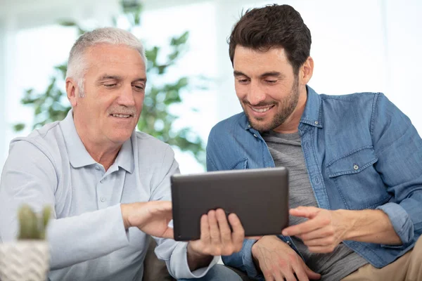 一个使用平板电脑的成年儿子和年长父亲 — 图库照片