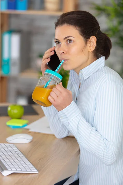 美しい若い女性のオフィスで柑橘類のジュースを飲む — ストック写真