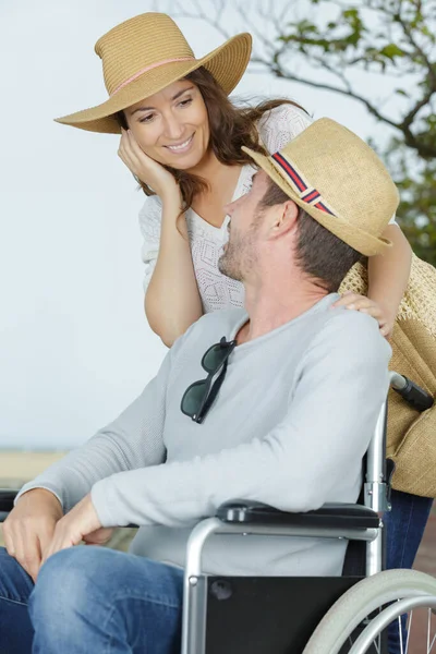 車椅子に縛られた夫に愛情を込めて話す女性は — ストック写真