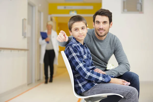 病院で医者を待っている間に笑顔の息子を持つ父 — ストック写真