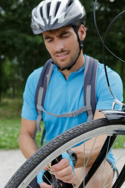 笑顔の男性サイクリストが自転車を修理する姿を — ストック写真