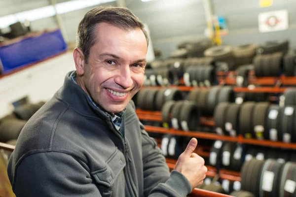 happy mechanic in tyre store warehouse