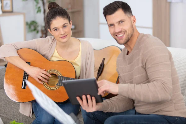 ハンサムな男が若い女性にギターを教える — ストック写真
