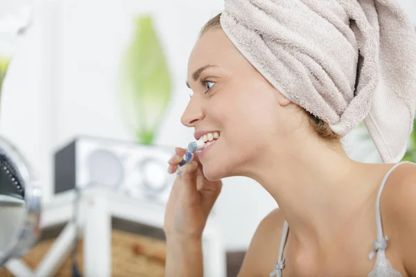 頭にタオルをつけた女性が歯を磨き — ストック写真