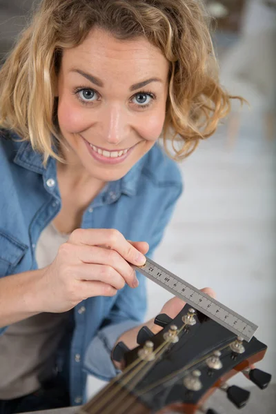 Женщина Измеряет Гитару Металлической Линейкой — стоковое фото