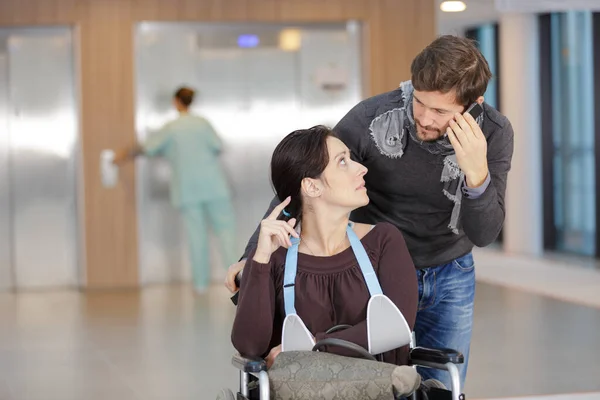 Mann Telefoniert Während Seine Frau Rollstuhl Schubst — Stockfoto